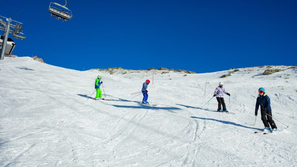 Four skiers following each other on a bluebird day.