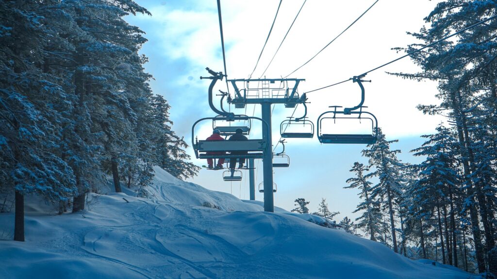 Two skiers on a chair lift at Attitash Mountain Resort.